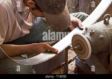 Homme aiguisant les lames de scie dans l'atelier de sculpture sur bois, Hotan, région autonome de Xinjiang, Chine. Banque D'Images