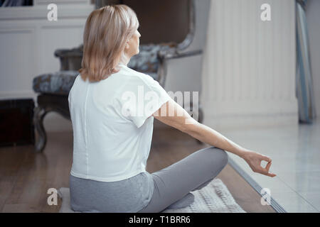 Une femme adulte médite après avoir fait du Yoga à la maison dans le salon. Banque D'Images
