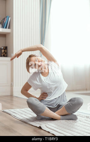 Des cours de yoga à la maison de belles femmes de plus de 50 ans. Banque D'Images