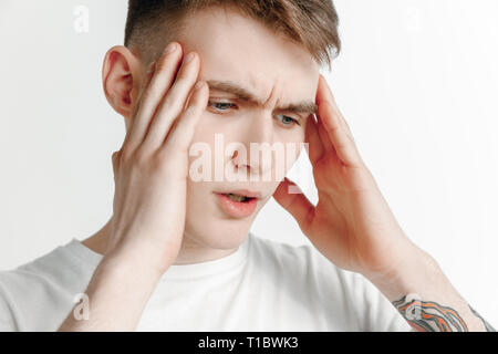 L'homme ayant des maux de tête. Business man standing avec douleur isolé sur fond studio gris. La moitié des hommes portrait en pied. Les émotions humaines, l'expression faciale concept Banque D'Images