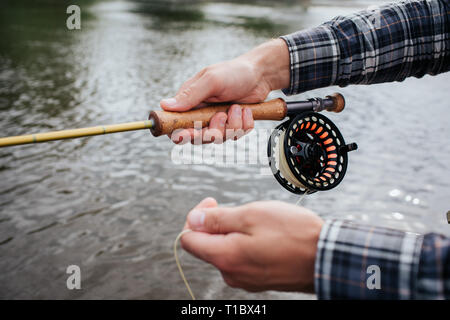 Une photo de man's hands holding la filature. Il y a une bobine non-à inertie sous canne à mouche. Guy est maintenant partie de cuillère dans la main. Banque D'Images