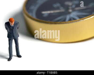 Figure miniature businessman en costume bleu foncé debout sur le côté de Golden Compass. Concept pour trouver la façon la façon de réussite des entreprises Banque D'Images