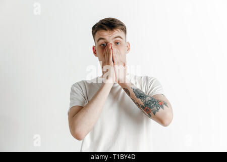 Pourquoi est-ce que c'est. Beau mâle half-length portrait studio isolé sur fond gris. Les jeunes surpris, frustrés et émotionnel de l'homme égaré. Les émotions humaines, l'expression faciale concept. Banque D'Images