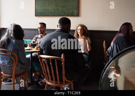 Divers amis parler autour d'un café tout en restant assis dans un café Banque D'Images