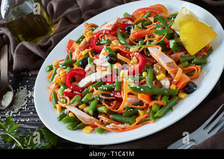 Salade mexicaine avec haricot vert, poivron, olives noires, carottes, maïs et jambon, saupoudré de graines de sésame sur une plaque blanche sur une table rustique avec d Banque D'Images