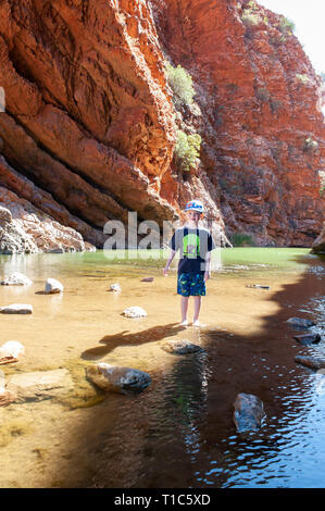 Un garçon de 6 ans joue sur le stepping stones dans les eaux peu profondes de Simpsons Gap, Territoire du Nord, Australie Banque D'Images