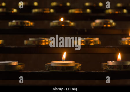 Bougies votives allumé comme prières pour les proches à l'intérieur d'une église chrétienne Banque D'Images