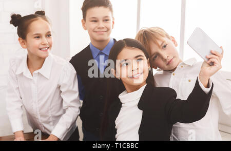 Les enfants de l'école prenant sur smartphone selfies in corridor Banque D'Images