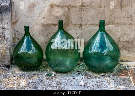 Trois énormes pots de vin vide en verre vert placé dans une ligne qui reflète l'architecture étonnante de Matera, Basilicate région, l'Italie et le moody nuageux s Banque D'Images