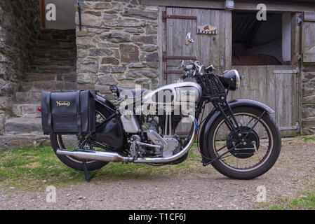 Vélo classique. Une moto Norton stationné près d'une ancienne en pierre est stable avec les portes en bois sur une ferme dans le Nord du Pays de Galles. Banque D'Images