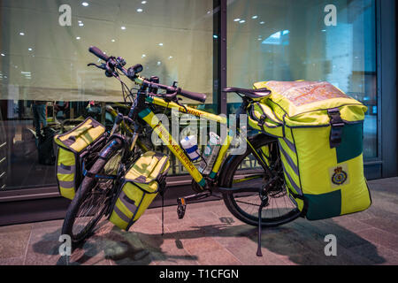 Vue latérale d'un paramédic pousser d'urgence, un vélo sur-mesure location, trousse médicale et spécialiste de l'habillement en stationnement sur son vélo à l'extérieur d'un London o Banque D'Images