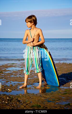 Beaux jeunes 8-10 ans garçon tirant un bodyboard à la plage Banque D'Images