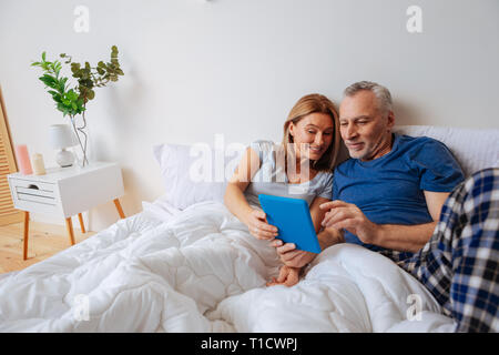 Mari aux cheveux gris et son épouse la lecture des nouvelles sur tablette Banque D'Images