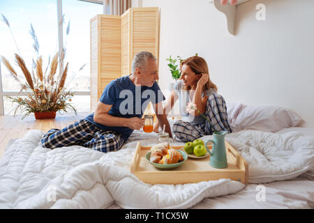 Hommes d'wearing pajamas profiter de week-end le petit-déjeuner en chambre Banque D'Images