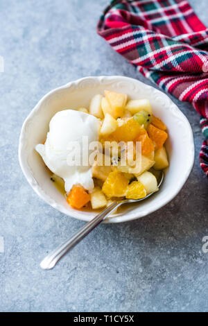 Salade de fruits avec glace à la vanille dans un bol en céramique prêt à manger. Banque D'Images