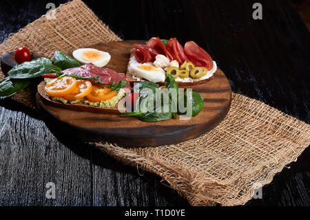 Sandwich au jambon et au fromage sur pain toast grillé sur un fond de bois avec du papier craft, légumes frais mûrs Banque D'Images