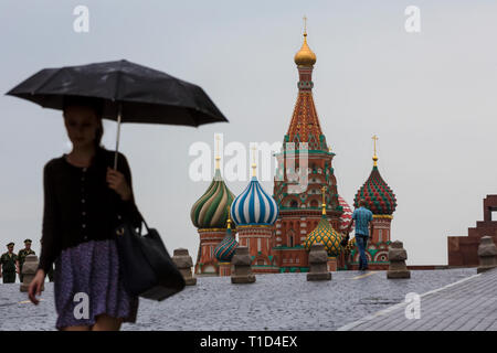 Temps de pluie à Moscou le jour d'été. Une fille qui marche avec parasol sur la place rouge sur l'arrière-plan de la cathédrale Saint-Basile, dans le centre de Moscou, Russie Banque D'Images