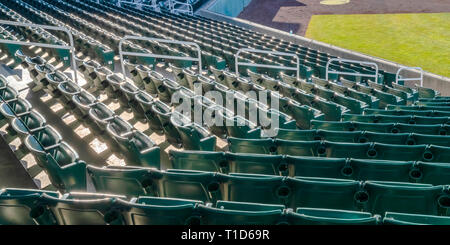 Arène de sport avec des gradins de sunlit sièges vides. Dans une arène de sports avec des niveaux de vide chaises vertes éclairées par la lumière du soleil. Pelouse et soignées Banque D'Images