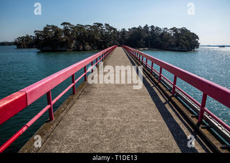 Sur la côte de Matsushima, Japon, un petit pont avec garde-corps rouge conduit les visiteurs à pied sur de Fukuurajima Banque D'Images