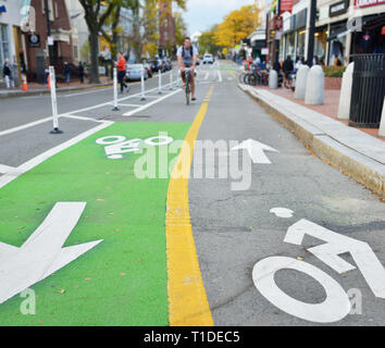 Deux voies de voies cyclables protégées. Les marqueurs de la chaussée peint en vert, jaune et blanc. Biker et people walking on city street Banque D'Images