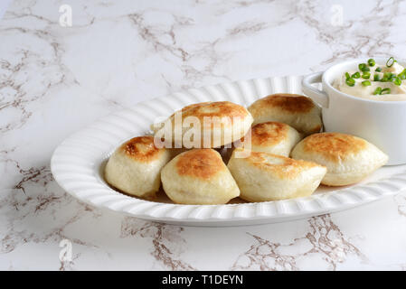 Pierogies avec de la crème et oignons de printemps Banque D'Images