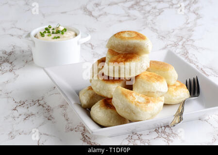 Pile des pierogies avec de la crème sure et les oignons de printemps et d'une fourchette Banque D'Images