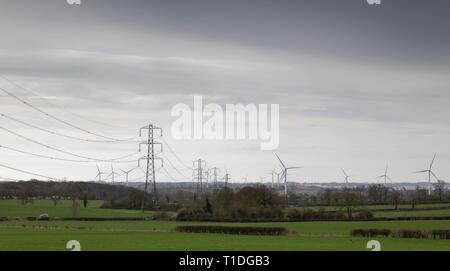 L'image d'un parc éolien et pylônes à la fois produire de l'électricité à la population du Royaume-Uni. Tourné à Swinford, Leicestershire, Angleterre, Royaume-Uni. Banque D'Images