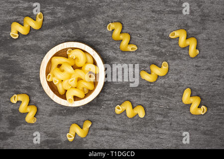 Beaucoup de pâtes cavatappi entier avec bol en bois en pierre grise sur flatlay Banque D'Images