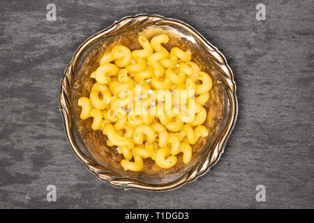 Beaucoup de pâtes cavatappi ensemble dans le vieux bol de fer flatlay sur pierre gris Banque D'Images