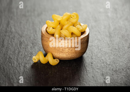 Lot de pâtes crues cavatappi avec bol en bois sur la pierre grise Banque D'Images