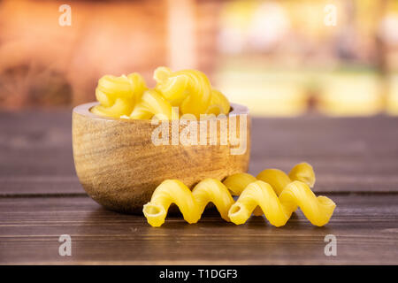 Lot de pâtes crues cavatappi avec bol en bois avec panier en arrière-plan Banque D'Images