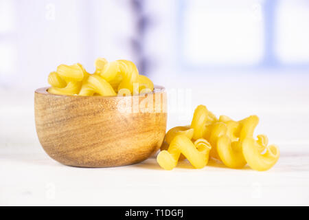 Beaucoup de pâtes cavatappi entier avec bol en bois avec fenêtre bleu en arrière-plan Banque D'Images