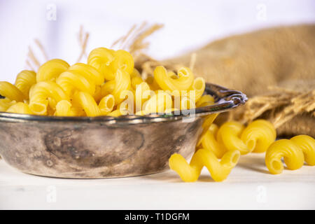 Lot de pâtes crues cavatappi dans de vieux bol de fer dans un sac de jute dans une cuisine blanche Banque D'Images