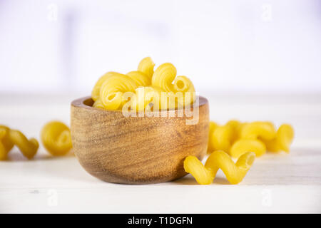 Lot de pâtes crues cavatappi avec bol en bois dans une cuisine blanche Banque D'Images