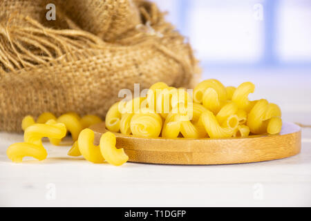 Beaucoup de pâtes cavatappi ensemble sur plaque de bambou dans un sac de jute avec fenêtre bleu en arrière-plan Banque D'Images