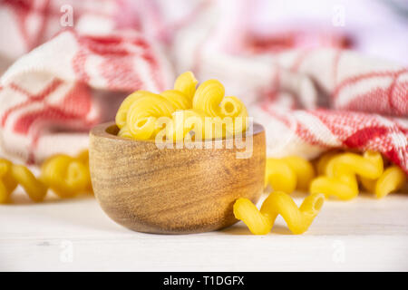 Lot de pâtes crues cavatappi avec bol en bois et un torchon dans une cuisine blanche Banque D'Images