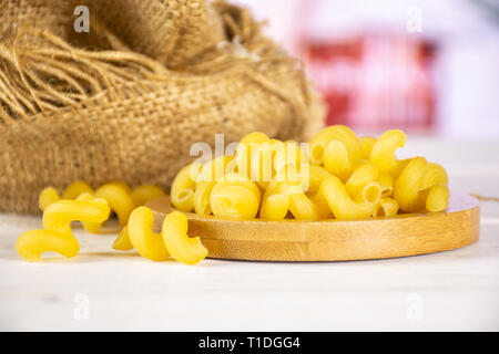 Beaucoup de pâtes cavatappi ensemble dans un sac de jute sur la plaque de bambou dans une cuisine blanche Banque D'Images