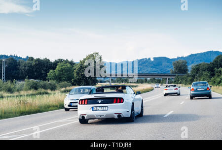 Schiltach, Allemagne - Jun 10, 2018 : l'autoroute allemande avec luxe blanc voiture cabriolet Mustang décapotable conduite rapide sur la route de campagne sur une journée ensoleillée avec des montagnes en arrière-plan de la Forêt-Noire Banque D'Images