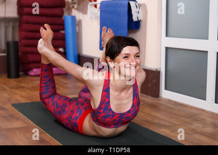 Young woman practicing yoga, faire des étirements Dhanurasana position dans un fitnes club. Banque D'Images