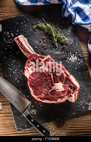 Steak de bœuf cru tomahawk avec sel poivre et romarin sur la plaque d'ardoise.