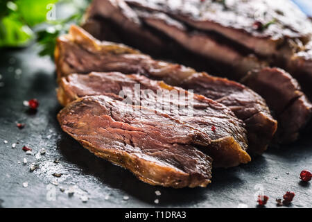 Pavé de boeuf grillé fraîchement sur ardoise plaque avec sel poivre et persil romarin herbes. Fabricants de pièces de bœuf juteux Banque D'Images