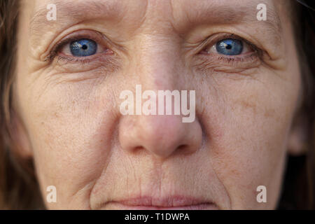 Portrait d'un visage aux yeux bleu femme d'âge moyen avec la peau ridée à l'objectif dans un concept du vieillissement Banque D'Images