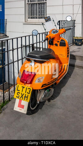 Close up vue arrière d'un scooter de moteur orange vif à l'extérieur une maison porte avant Banque D'Images