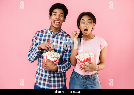 African-american couple eating popcorn sur fond rose Banque D'Images