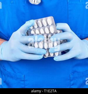 Médecin en uniforme bleu et des gants stériles holding white pills en pack, Close up Banque D'Images