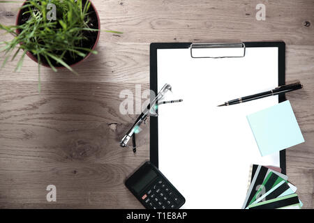 Vue de dessus.Presse-papiers avec une feuille blanche, un stylo, lunettes et calculatrice sur fond de bois Banque D'Images