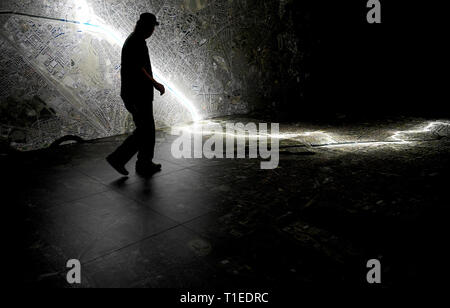 Berlin, Allemagne. Mar 25, 2019. Un jeune homme marche sur une photo aérienne de Berlin, marquant le tracé du mur et des lieux qui avait à voir avec la Stasi. Le spectacle avec le titre 'Stasi à Berlin - La surveillance et la répression dans l'Est et l'Ouest' affiche l'infrastructure cachés de la Stasi et sera ouverte le 28 mars 2019 dans la Hohenschönhausen Memorial. (Pour dpa 'Nouvelle exposition : les réunions de la Stasi, Photo aérienne, des comprimés) Credit : Britta Pedersen/dpa-Zentralbild/dpa/Alamy Live News Banque D'Images