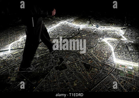 Berlin, Allemagne. Mar 25, 2019. Un jeune homme marche sur une photo aérienne de Berlin, marquant le tracé du mur et des lieux qui avait à voir avec la Stasi. Le spectacle avec le titre 'Stasi à Berlin - La surveillance et la répression dans l'Est et l'Ouest' affiche l'infrastructure cachés de la Stasi et sera ouverte le 28 mars 2019 dans la Hohenschönhausen Memorial. (Pour dpa 'Nouvelle exposition : les réunions de la Stasi, Photo aérienne, des comprimés) Credit : Britta Pedersen/dpa-Zentralbild/dpa/Alamy Live News Banque D'Images