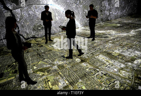 Berlin, Allemagne. Mar 25, 2019. Les gens marchent avec bacs sur une photographie aérienne de Berlin, marquant le tracé du mur et les lieux liés à la Stasi. Le spectacle avec le titre 'Stasi à Berlin - La surveillance et la répression dans l'Est et l'Ouest' affiche l'infrastructure cachés de la Stasi et sera ouverte le 28 mars 2019 dans la Hohenschönhausen Memorial. (Pour dpa 'Nouvelle exposition : les réunions de la Stasi, Photo aérienne, des comprimés) Credit : Britta Pedersen/dpa-Zentralbild/dpa/Alamy Live News Banque D'Images