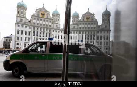 26 mars 2019, la Bavière, Augsbourg : l'hôtel de ville et une voiture de police se reflètent dans une vitrine. Après un appel à la bombe, la place centrale dans le centre-ville a été fermée après une menace de violence. L'hôtel de ville a été évacué au cours de la vaste opération policière. Les lignes de tram en travers de la place de l'Hôtel de ville ont été arrêtés. Photo : Stefan Udry/dpa Banque D'Images